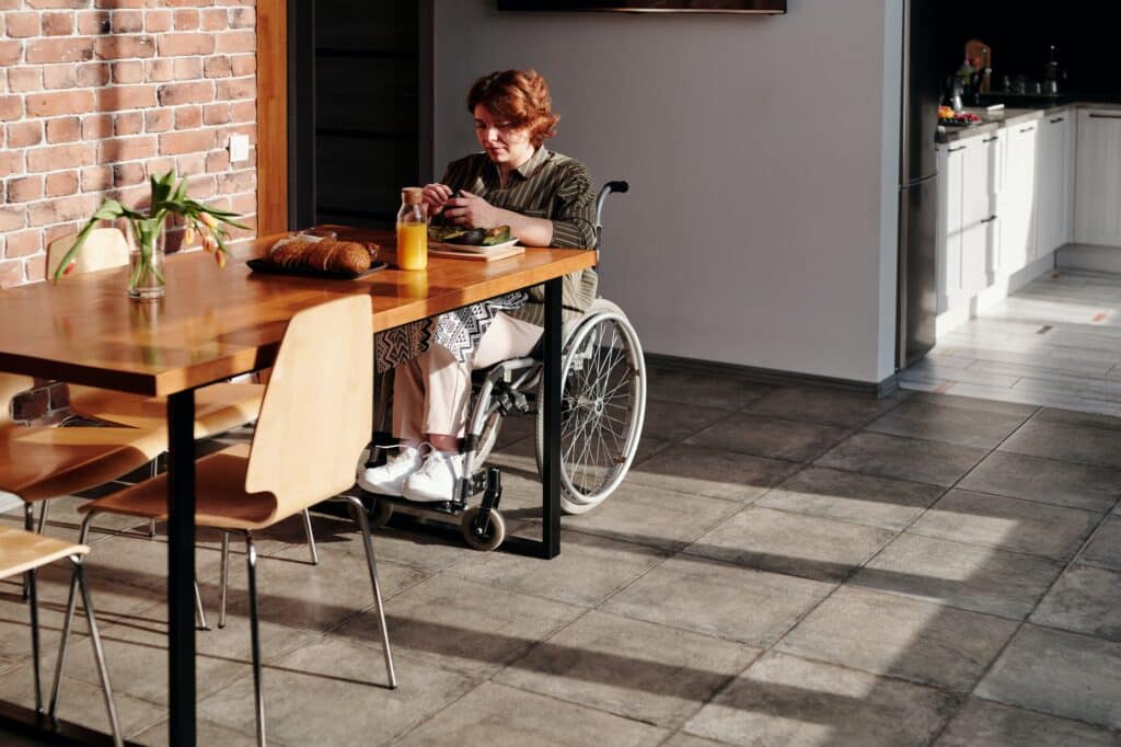 red haired woman in a wheelchair preps breakfast in her kitchen before making a wheelchair to car transfer