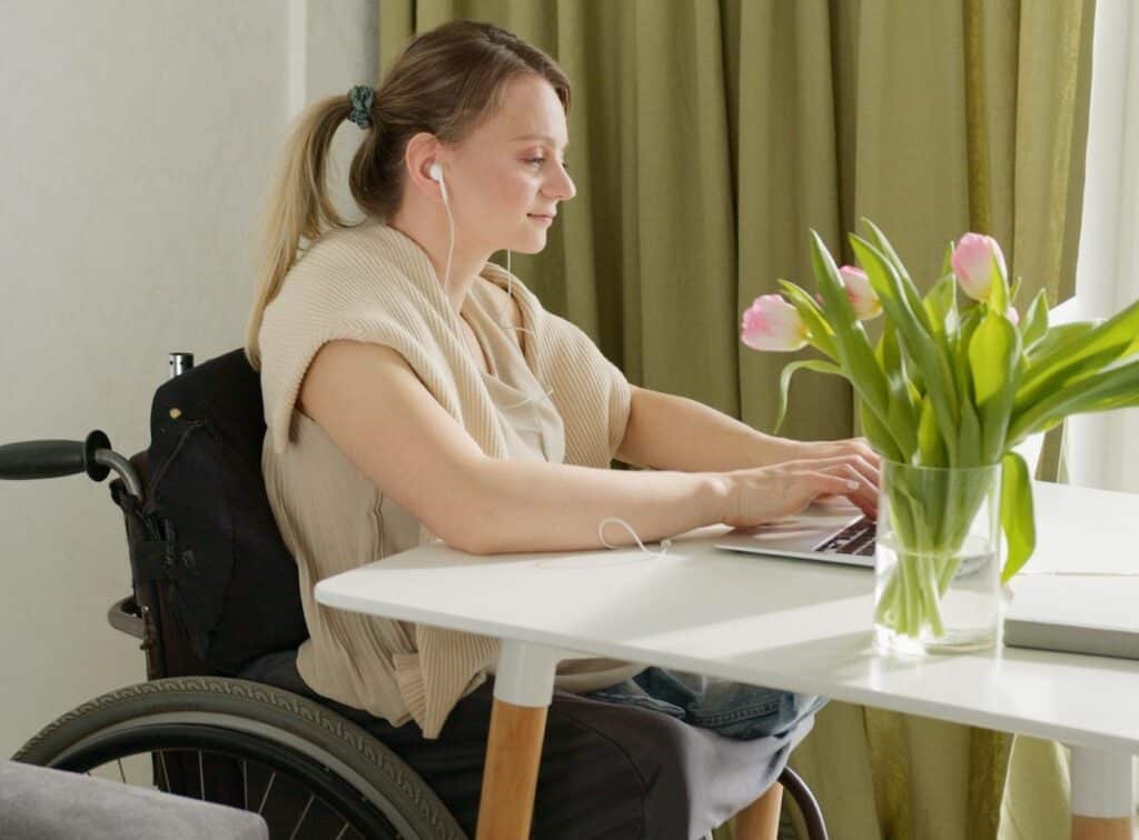 woman with a ponytail sitting at a tabler with pink flowers googles 'How to ease transferring from your wheelchair to car?'