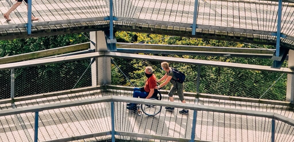 a man pushes his father along a sightseeing bridge in a wheelchair 