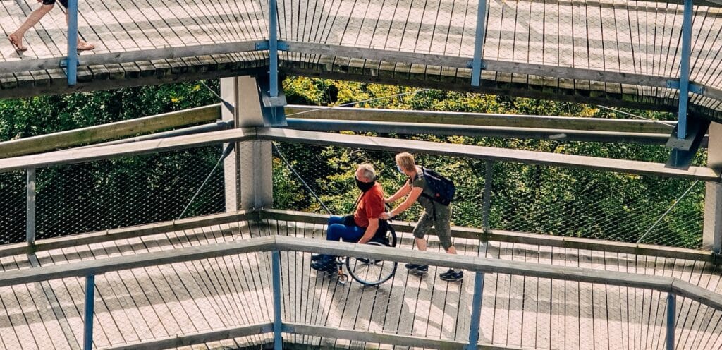 a man pushes his father along a sightseeing bridge in a wheelchair
