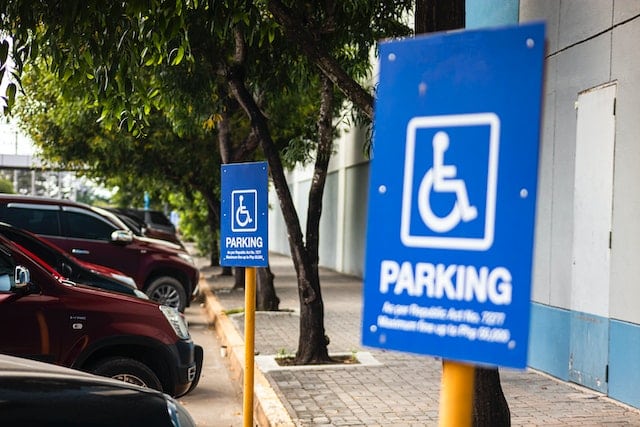 Image of a disabled parking sign on a street with a public transport vehicle in the background.
