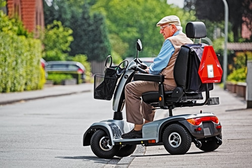 A man rides his mobility scooter on and off pavement through his neighbourhood