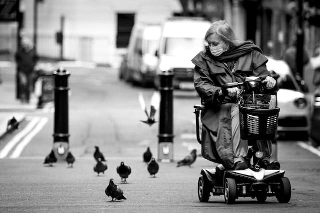 a woman rides a daily hire mobility scooter through town