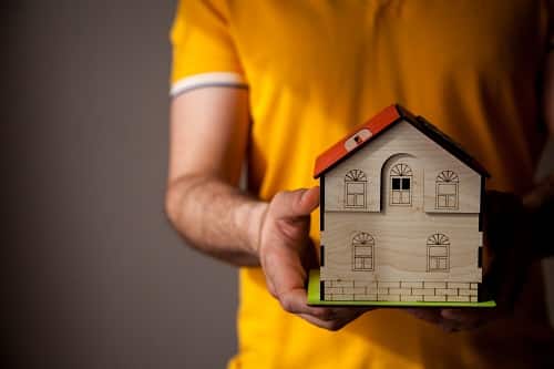 A man holding a wooden house. You may be on the lookout for disability housing