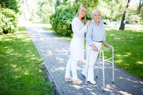 Nurse helping senior woman to use walking frame. Mobility aids provide independence and confidence.