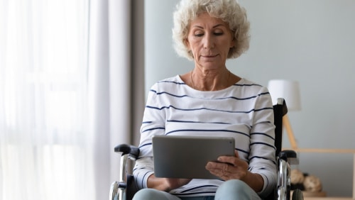 This photo shows an elderly woman in a wheelchair using one of the apps for people with disabilities, it may be a speech to text app