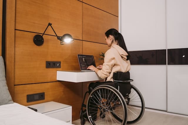 A woman works from her accessible bedroom on a desk designed for disability access