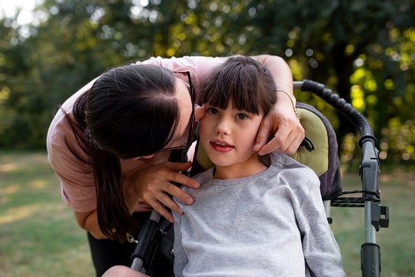 A child in a wheelchair, she may have CP - a motor disability