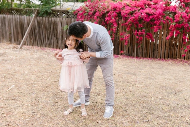 A young girl with CP, being held by her father