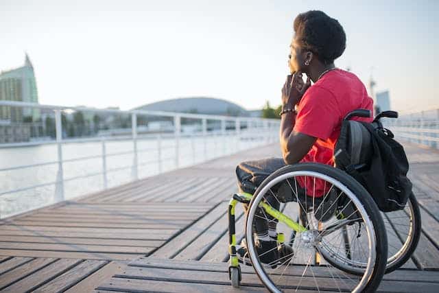 A young Australian man looks out over a waterway, contemplating the NDIS transport funding criteria