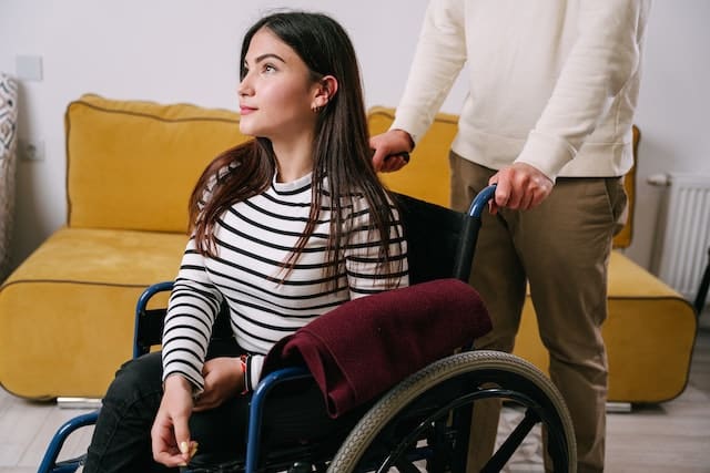 A man helps his wife who is in a wheelchair get ready to leave their home to stay at a relative's house during the peak of Australian bushfire season