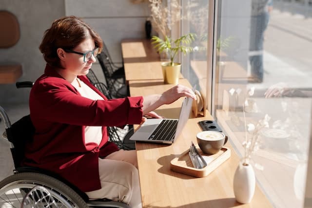 A woman in a wheelchair completing a disability parking permit application online.