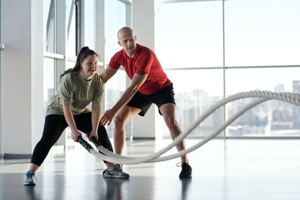 Two people working out with ropes in a gym to promote inclusivity on the International Day of Persons with Disabilities 2023 (IDPWD).