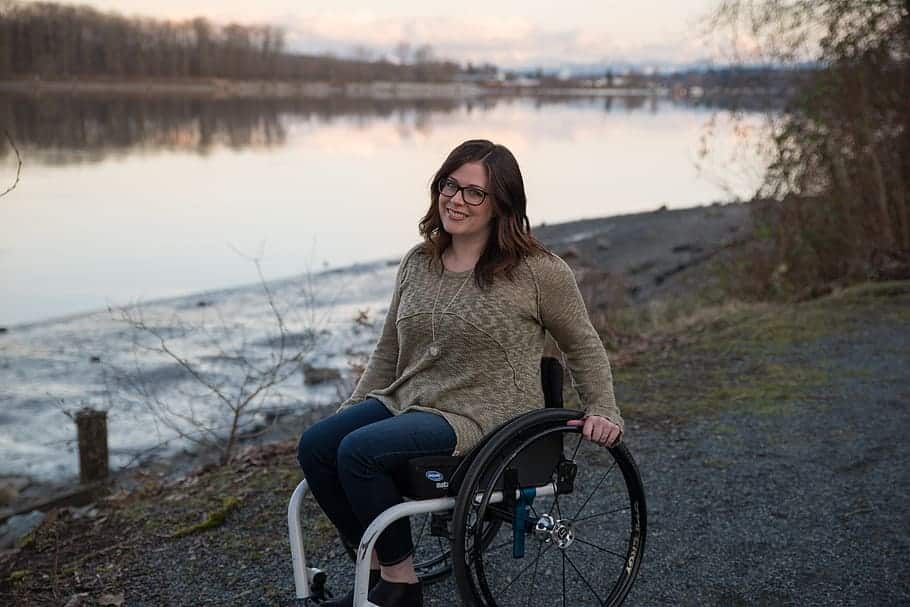 A woman in a wheelchair spends some downtime at a lake during her wheelchair accessible vehicle road trip