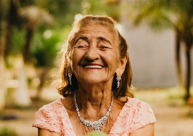 An elderly woman, eligible for home care packages, is holding a green apple.