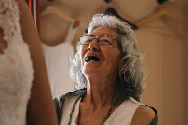 An older woman joyfully chats with her carer who has arrived back following a break during which a respite carer stood in. 