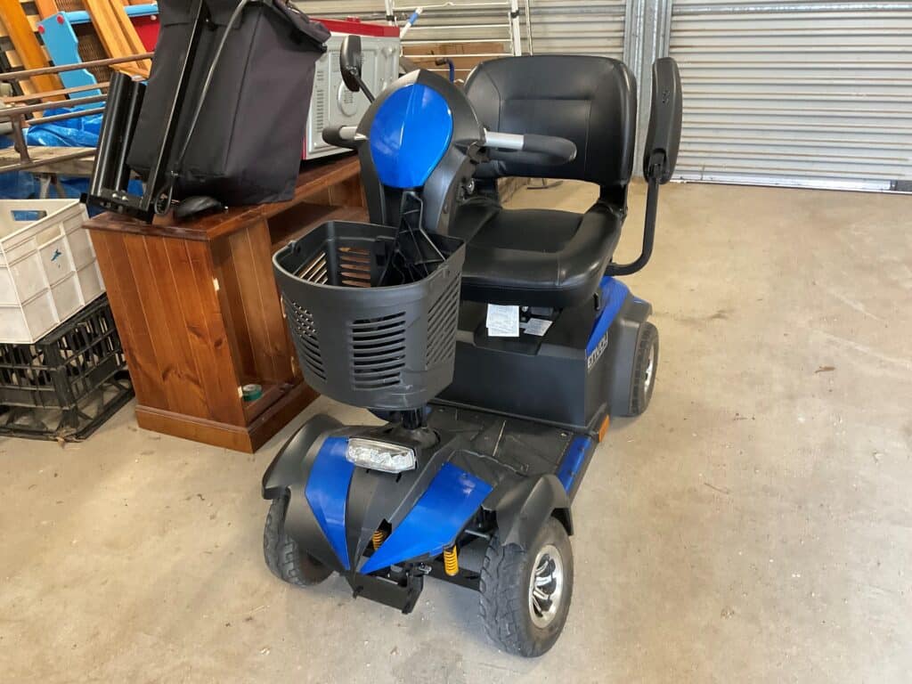 A blue and black scooter is parked in a garage, showcasing its excellent mobility scooter parts.