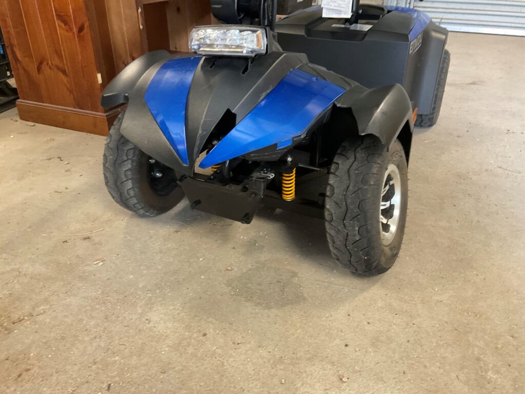 A blue and black mobility scooter, sitting in a garage.