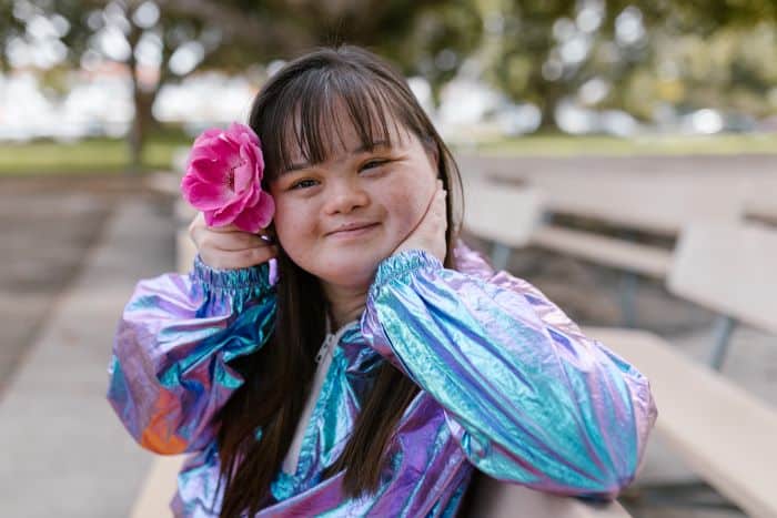 A young girl with a flower in her hair sitting on a bench, captured in one of our most popular blog posts.