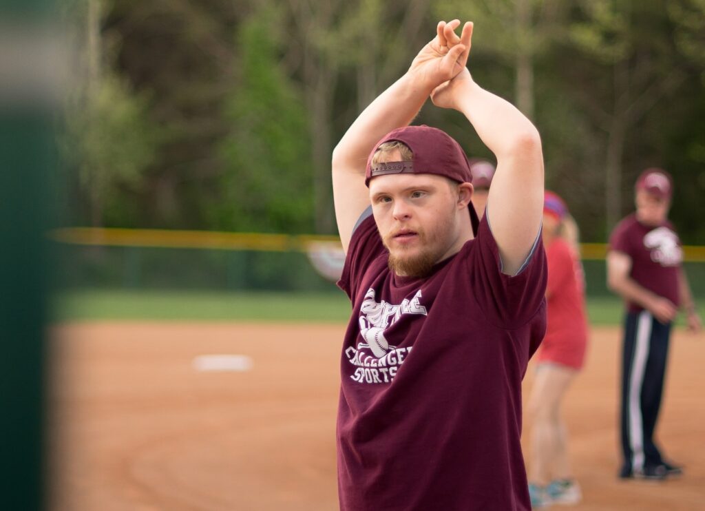 A man who lives with disability is stretching on a sports track before participating in sports. 