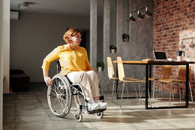 A woman with a wheelchair sitting in a room, ensuring her home insurance contents cover includes specialised insurance.