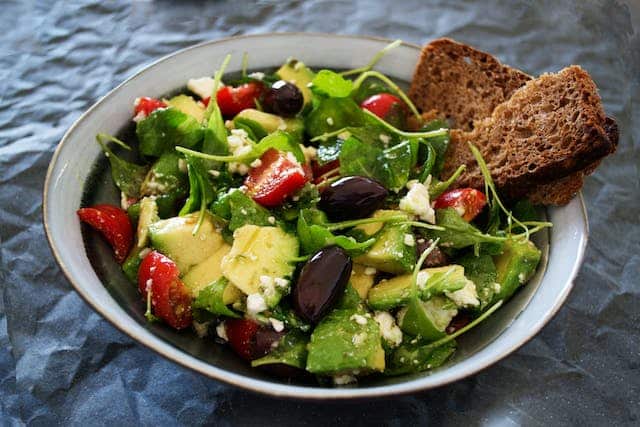 A refreshing bowl of salad with juicy tomatoes, briny olives, and tangy feta cheese prepped as part of the healthy diet of someone recovering from bedsores.