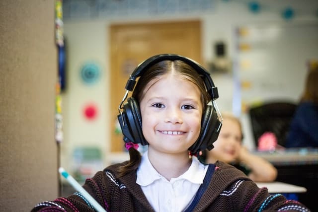 A young girl wearing headphones in a classroom explores inclusive learning practices that cater to her neurodiversity