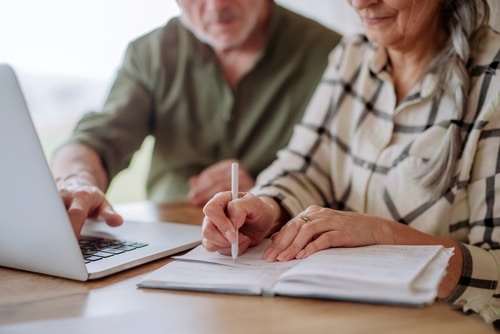 A man and woman engaged in the NDIS scheme review process, writing in a notebook.