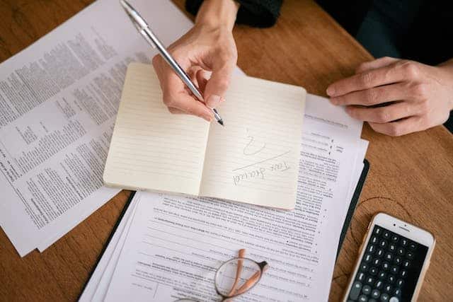 A person carefully writing on a paper with a pen, ensuring there is no spot left untouched.