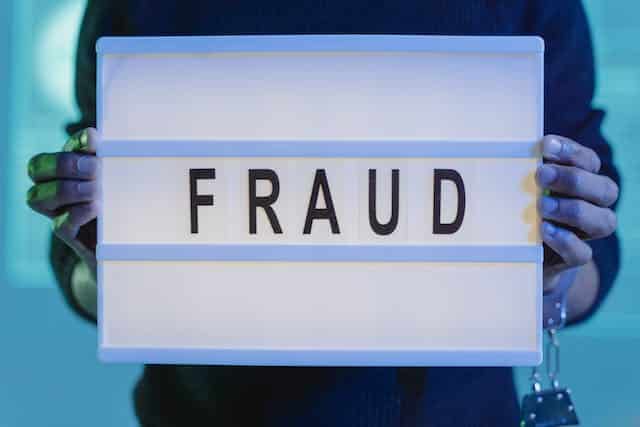An experienced individual carefully spotting NDIS fraud, holding up a sign that says fraud.