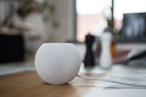 A white speaker sits on top of a wooden table, providing adaptive art supplies for disabled adults.