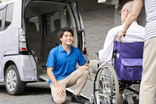 A man receiving assistance from another man in a wheelchair under the NDIS scheme review.