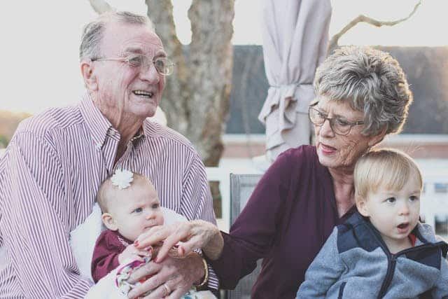 An older couple representing the large portion of Australians who are baby boomers sit on a patio with their two grandchildren