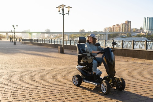 A woman is riding a motorized scooter on a sidewalk and accidentally causes damage.