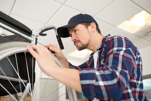 A man is seen repairing a wheelchair.