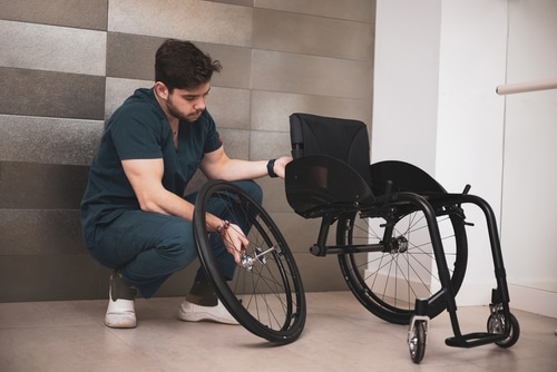 On World Wheelchair Day, a man adjusts the wheel of a wheelchair.