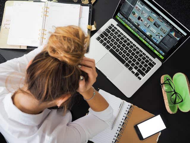 A woman with autism is sitting at a desk with a laptop, navigating workplace struggles.