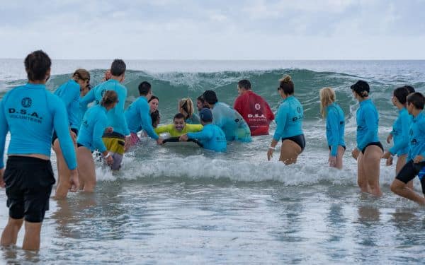 Group of volunteers and participants enjoying a surfing with disabilities activity at the beach with the Disabled Surfers Association of Australia.